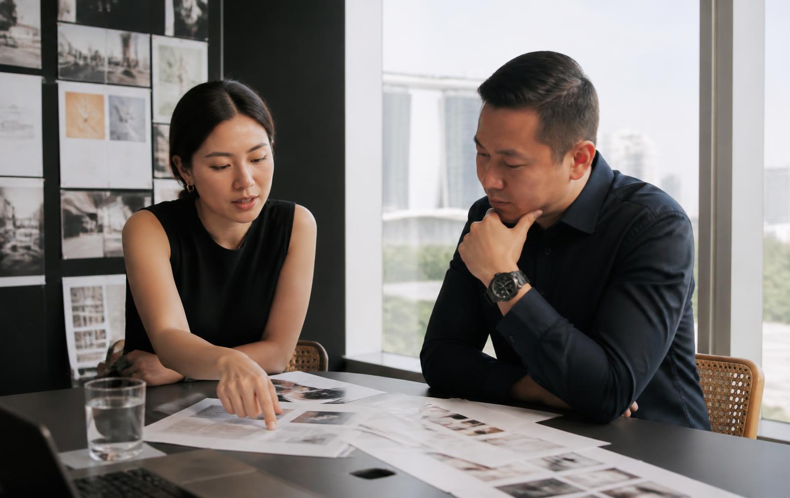 A client and agency strategist reviewing brand and campaign materials together in a Singapore meeting room