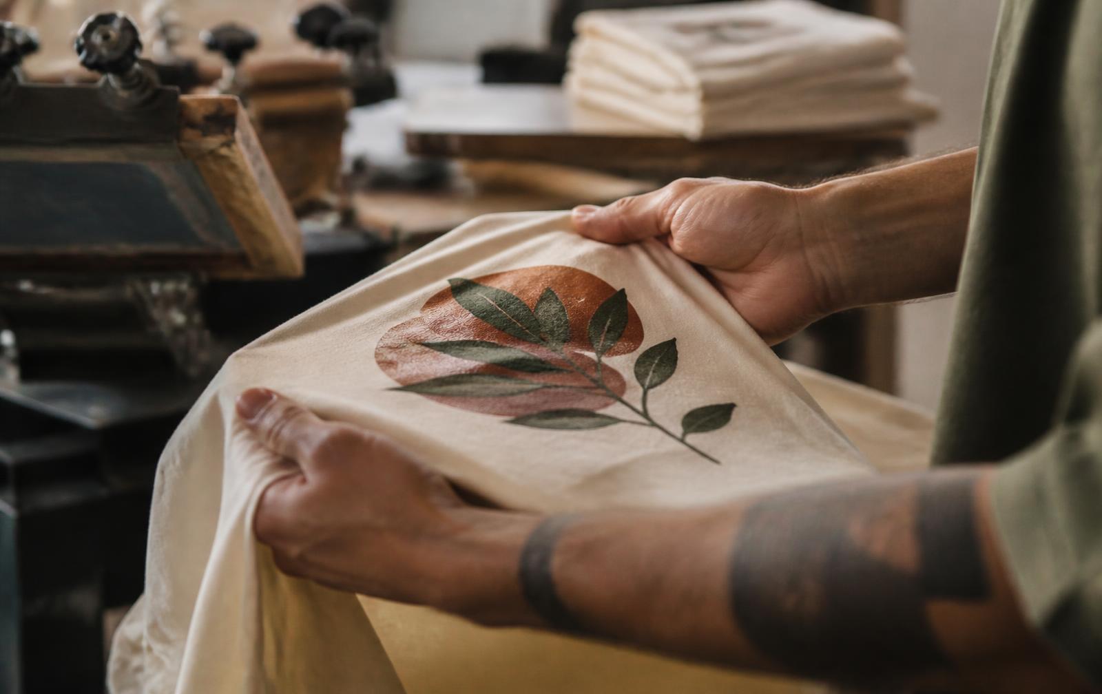 Checking print quality on a freshly screen-printed cotton tee in a production workshop