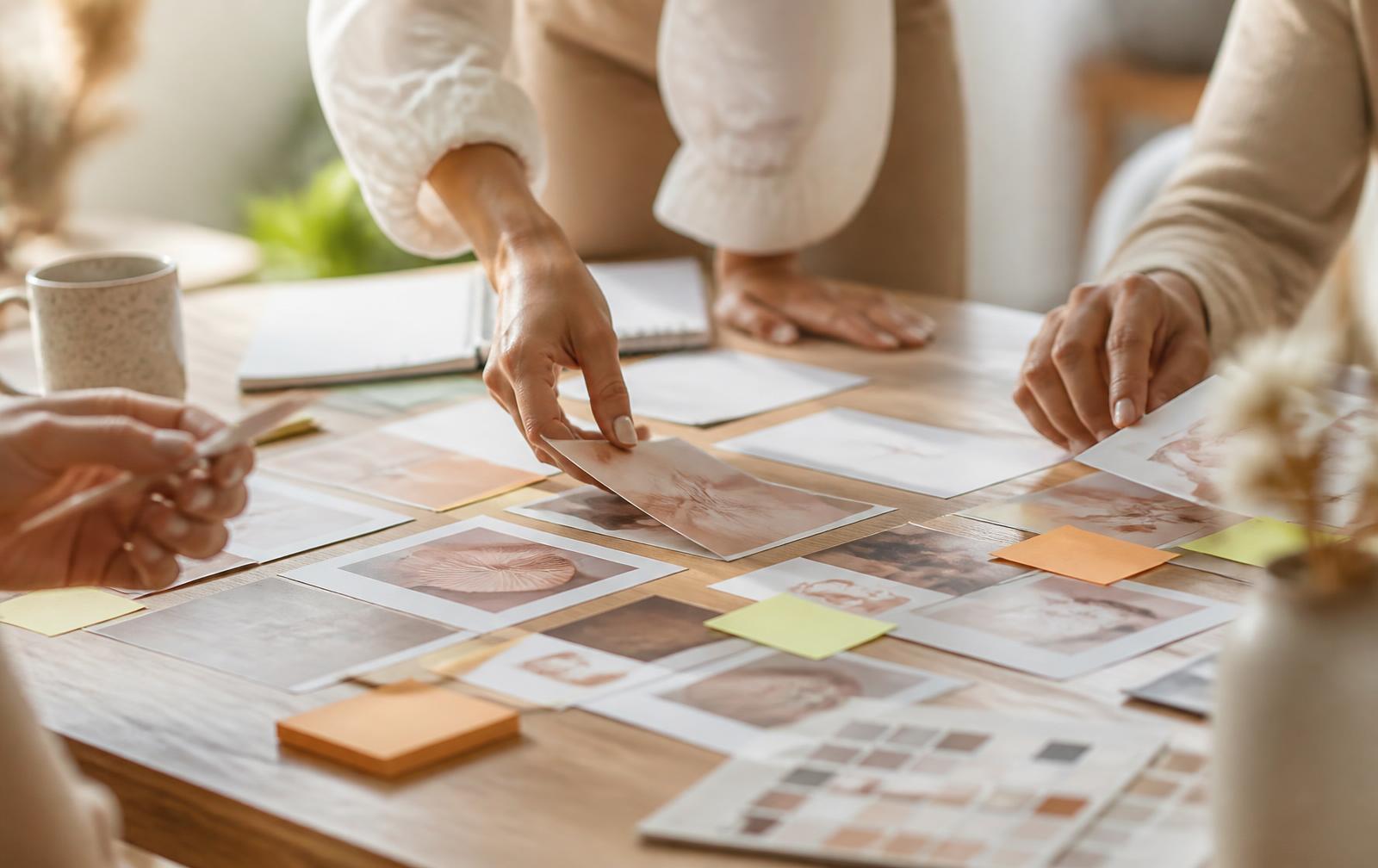 Planning a monthly social media content calendar with printed post layouts on a table